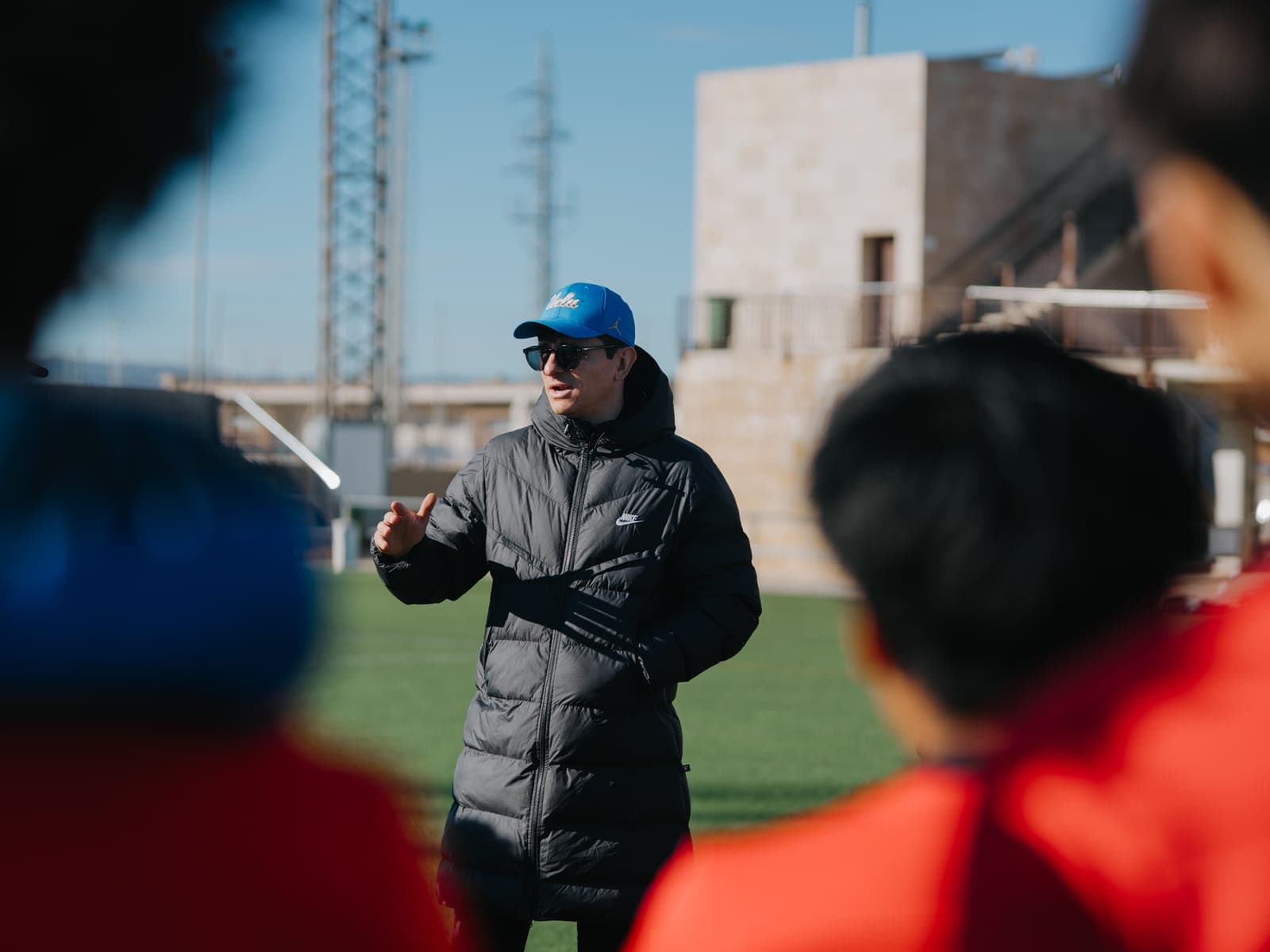 Un entrenador universitario hablando con jugadores de Eture a pie de campo